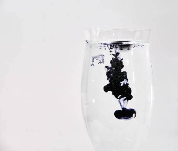 istock Blue and black ink dropping into a wine glass 1196753029