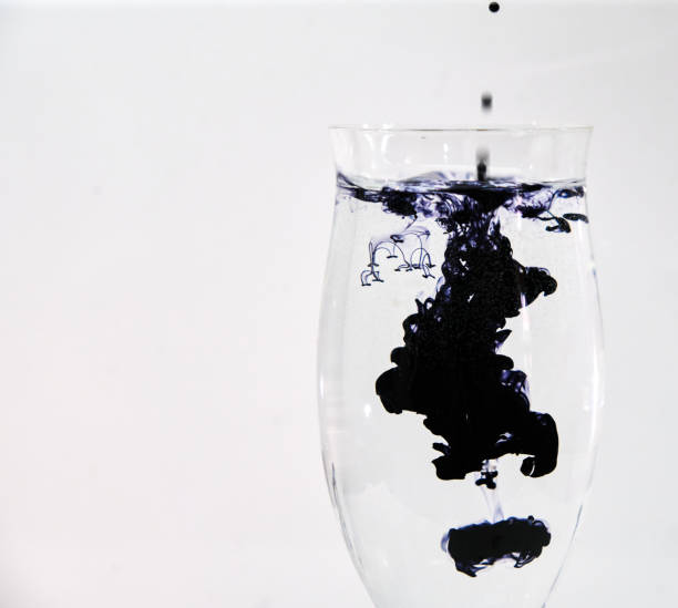 istock Blue and black ink dropping into a wine glass 1196753664