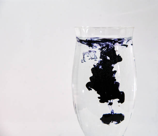 istock Blue and black ink dropping into a wine glass 1196753668