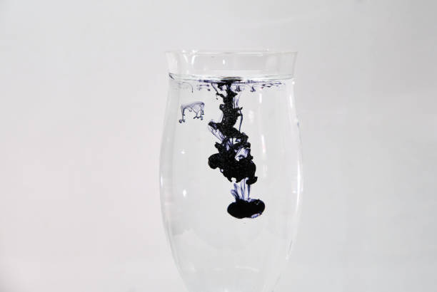 istock Blue and black ink dropping into a wine glass 1196753792