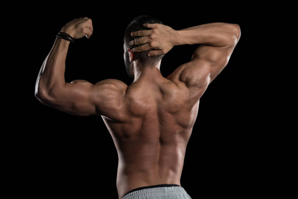 istock Muscular Model Flexing Muscles On Black Background 1196754094