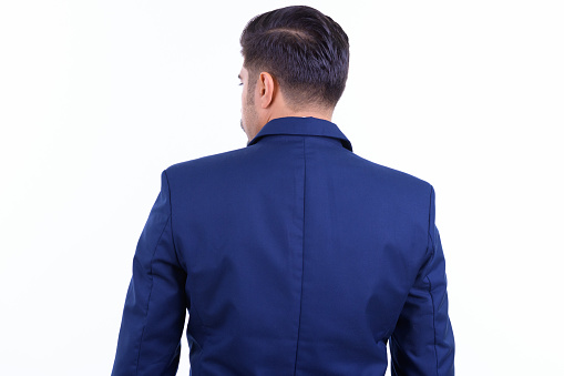 Studio shot of young handsome bearded Iranian businessman in suit isolated against white background