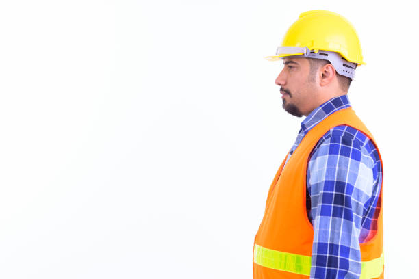 Studio shot of young handsome bearded Iranian man construction worker isolated against white background