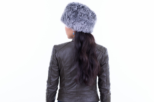 Studio shot of beautiful Asian woman wearing fur hat ready for winter isolated against white background