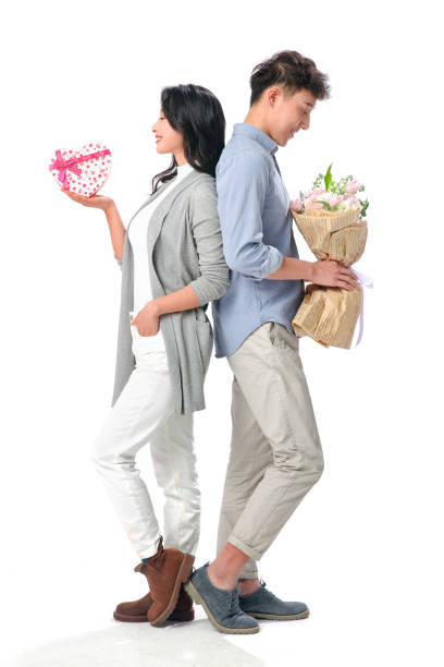 Casual couple in warm clothing holding gift on white background