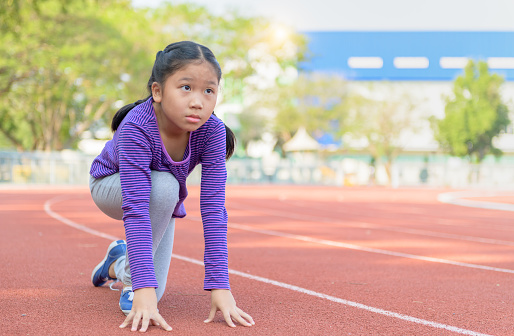 Cheerful cute girl in ready position to run on track, healthy and exercise concept.