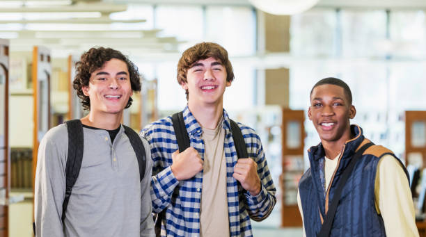 istock Three teenage boys standing in library smiling at camera 1196769617