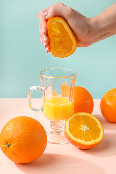 istock Oranges, a transparent glass and a juicer. Bright background, creative frame, fashion light. Pastel colors. Concept of modern and fashionable. Summer mood and vitamins. 1196781156