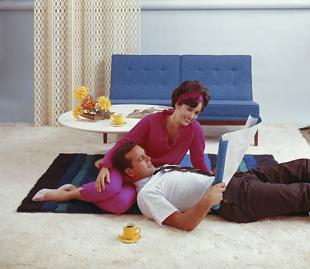 paar blick auf blaupause im wohnzimmer, lächelnd - 1950 1959 stock-fotos und bilder