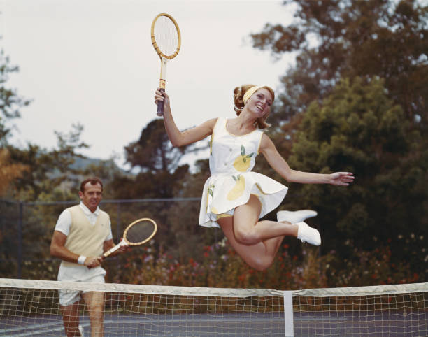 Couple on tennis court, woman jumping in foreground  tennis outfit stock pictures, royalty-free photos & images