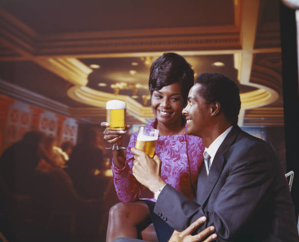 casal jovem segurando um copo de cerveja, sorrindo - 1966 - fotografias e filmes do acervo