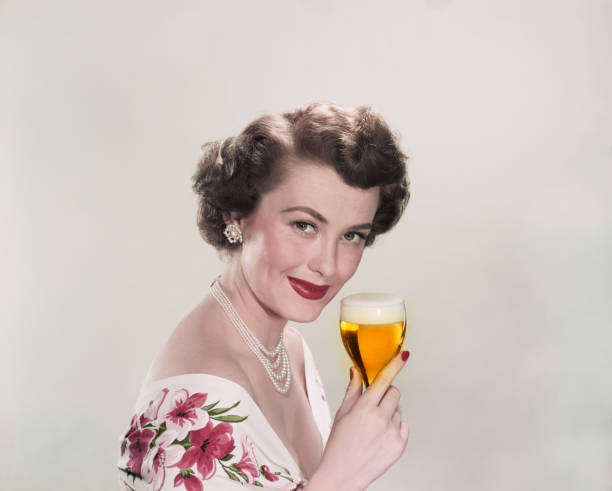 Young woman holding glass of beer, smiling, portrait  vintage women stock pictures, royalty-free photos & images