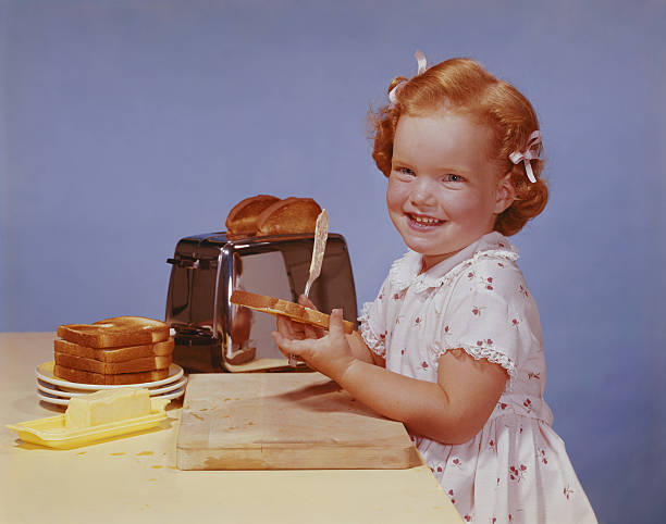 Girl spreading butter on toast, smiling, portrait  butter photos stock pictures, royalty-free photos & images
