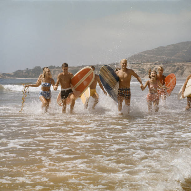 groupe de surfers courant dans l'eau avec des planches de surf, souriant - ankle deep in water photos et images de collection