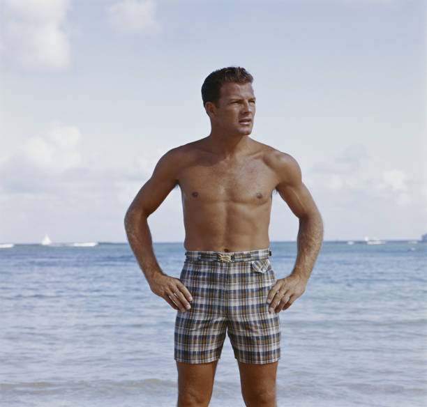 mann stehend am strand - swimming trunks fotos stock-fotos und bilder