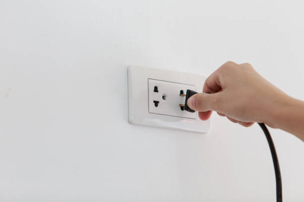 istock Hand Putting Plug Into Electricity Socket on clean cement plaster wall background. Unplug or plugged and pull electric plug 1196786742
