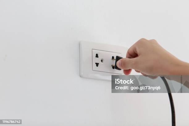 Hand Putting Plug Into Electricity Socket On Clean Cement Plaster Wall Background Unplug Or Plugged And Pull Electric Plug Stock Photo - Download Image Now