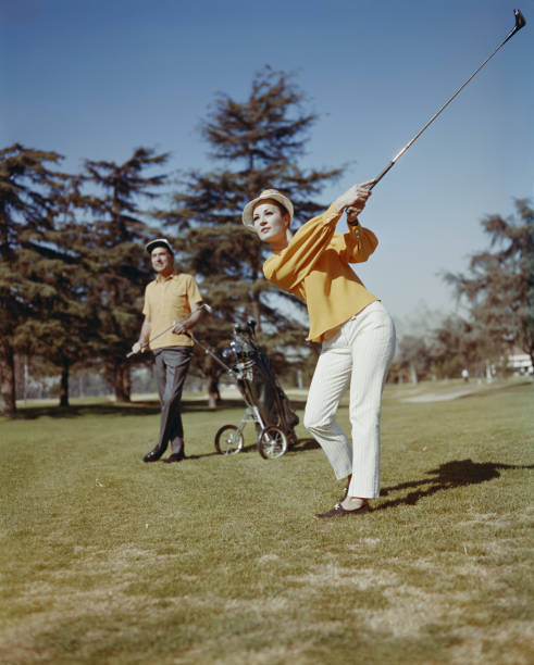 Young women playing golf while man standing in background  1968 stock pictures, royalty-free photos & images