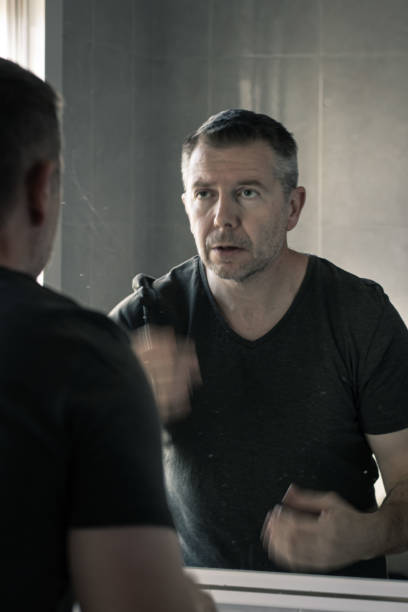 istock Man in a grey v-neck tshrt looking at himself in mirror gesturing with hands in blurred motion 1196788277