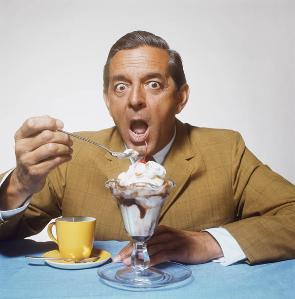 Mature man eating sundae against white background, close-up  1968 stock pictures, royalty-free photos & images