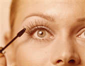 Woman applying mascara, close up