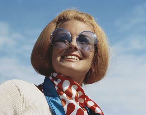 Mujer joven lleva gafas de sol y sonriendo, primer plano photo