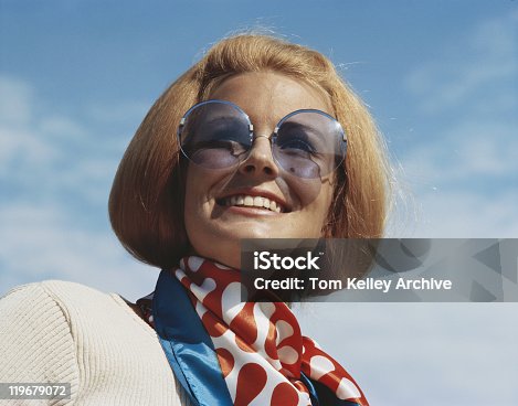 istock Young woman wearing sunglasses, smiling, close-up 119679072