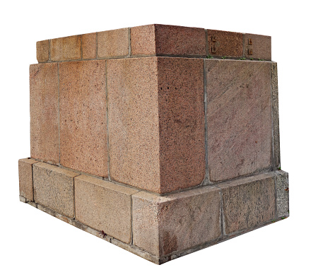 The base for a old aged statue made of roughly processed big granite aged blocks. Isolated on white