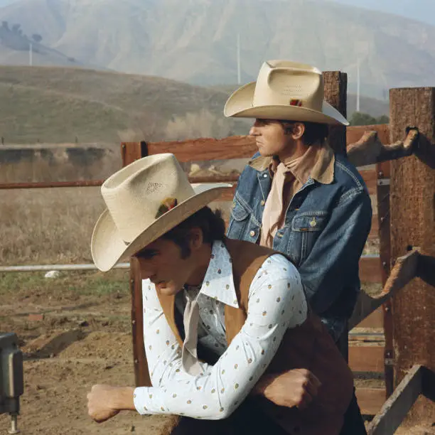 Photo of Young cowboys leaning on fence