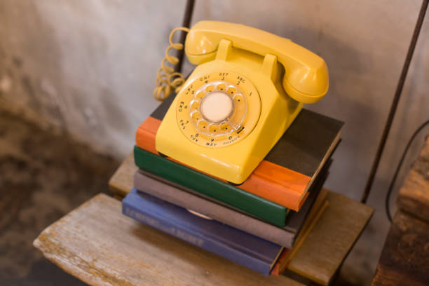 Old yellow rotary phone on the book stock photo