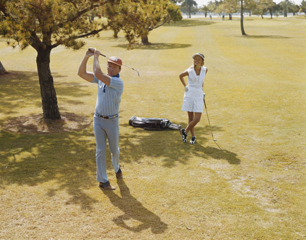 älteres paar golf spielen, mann schwingende golf club - sports venue clothing outdoors front view stock-fotos und bilder