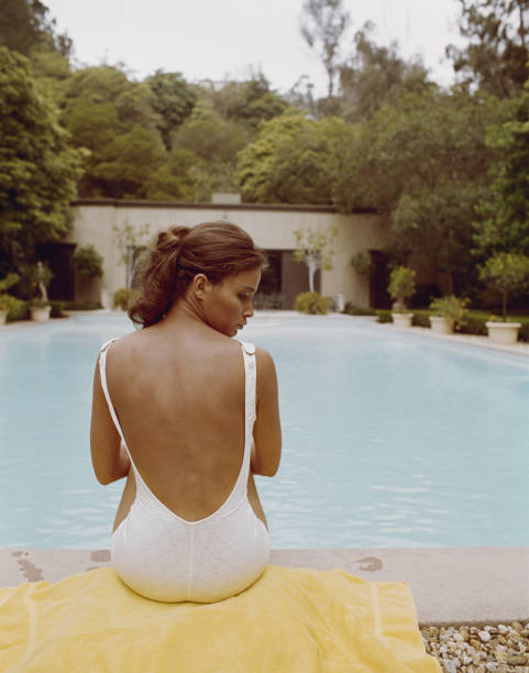 Young woman sitting at edge of swimming pool  1974 photos stock pictures, royalty-free photos & images
