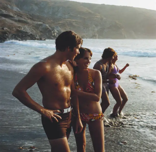 Photo of Young couples standing on beach, smiling