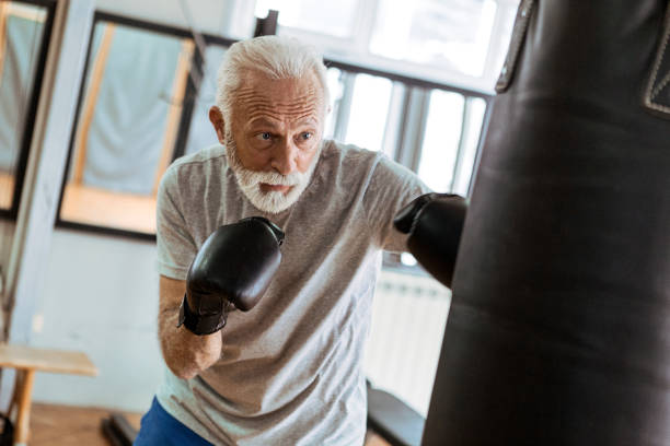 Senior training boxing with punching bag Senior in gym boxing old man boxing stock pictures, royalty-free photos & images