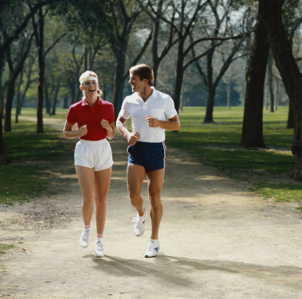 couple de jogging dans le parc, souriant - vintage toning photos et images de collection