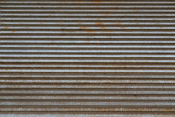 Weathered stainless steel roll up door. Rusty iron gate. Metal roller door. Metallic roller shutter door background
