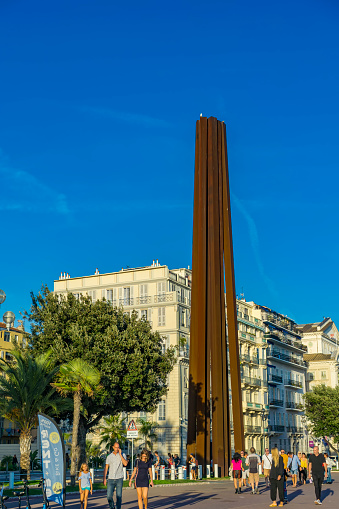 Unidentified people by Neuf lignes obliques monument in Nice, France. This steel monument on the Promenade des Anglais, was made by French artist Bernar Venet at 2010.