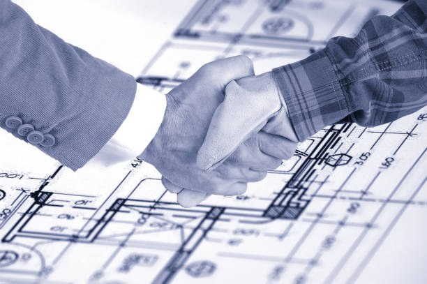 Worker and a businessman shaking hands over house renovation plans Worker and a businessman shaking hands over house renovation plans, renovation contract deal and plans autocad house plans stock pictures, royalty-free photos & images
