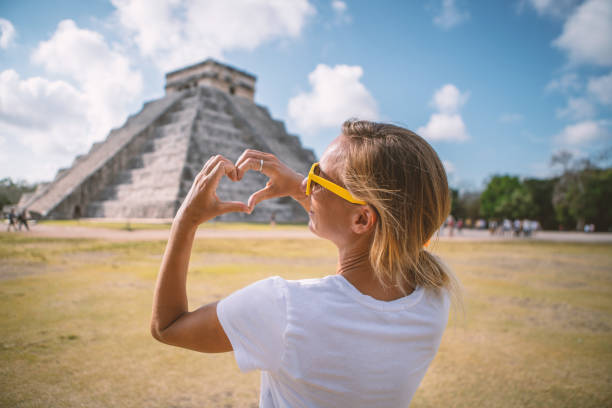 istock Young woman making heart shape on Chichen Itza pyramid, Mexico 1196810529