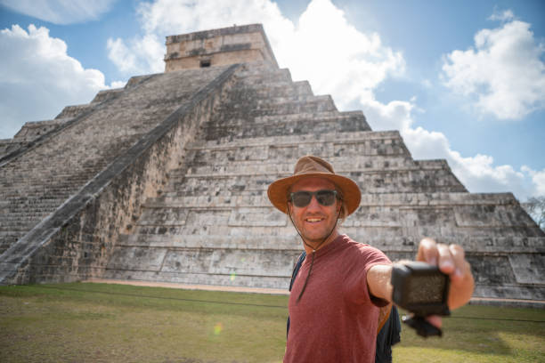 istock Young man taking selfie portrait in front of Chichen Itza temple 1196810709