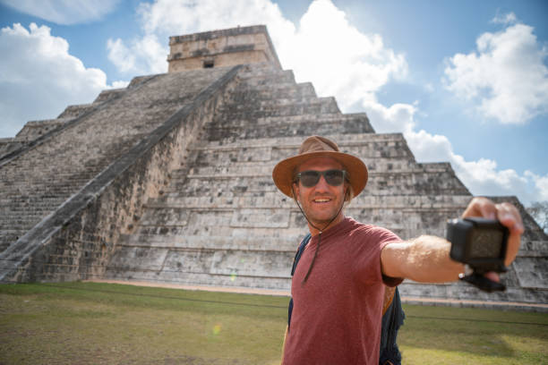 istock Young man taking selfie portrait in front of Chichen Itza temple 1196810738
