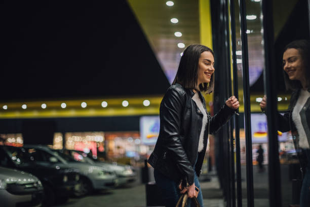 istock Young woman is looking at store window 1196812492