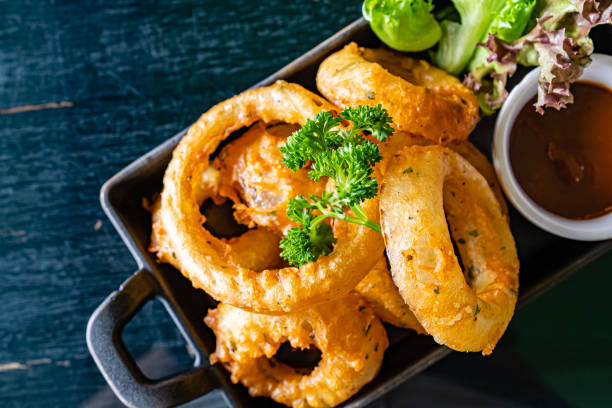 os anéis fritados da cebola serem com molho do assado na placa de ferro preta - parsley spice herb garnish - fotografias e filmes do acervo