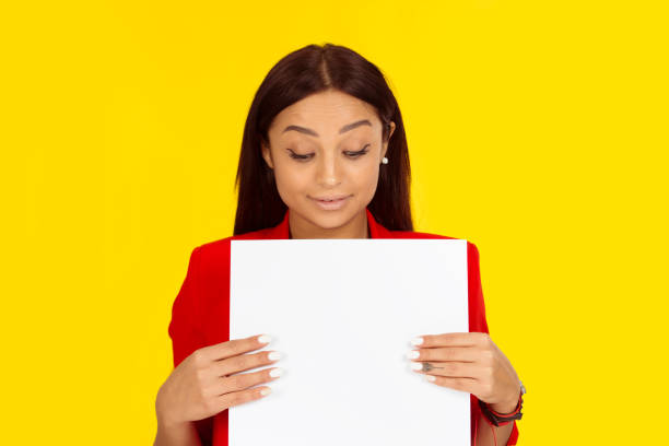 istock woman curious looking down at a white blank paper board. 1196815253