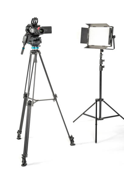 professional cinema video camera on a camera tripod and a professional lighting fixture on white studio background - television camera tripod media equipment videography imagens e fotografias de stock