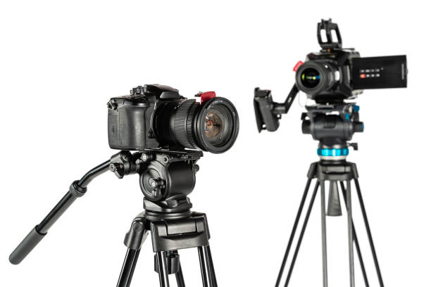 istock Cinema video camera and DSLR mirrorless camera on tripods on white studio background focus on foreground 1196815472