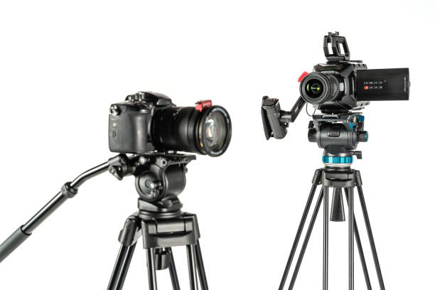 istock Cinema video camera and DSLR mirrorless camera on tripods on white studio background focus on background 1196816116