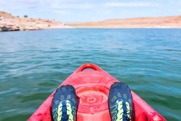Kayaking in Lake Powell to antelope canyon with feet water shoes at front of red kayak boat and blue turquoise water