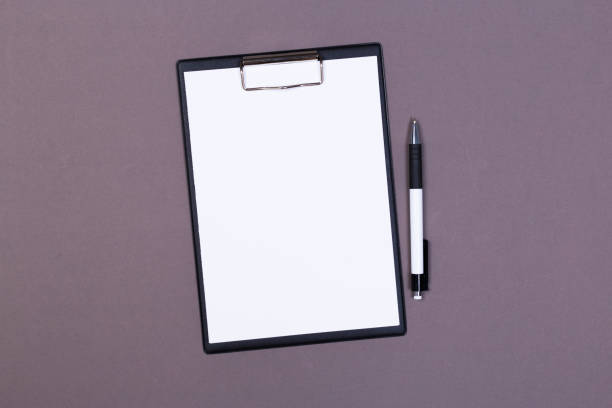 Clipboard with white sheet and pen on a colored background. View from above. space for text