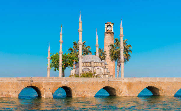 moschea centrale sabanci, vecchia torre dell'orologio e ponte di pietra ad adana, città della turchia. adana city con minareti della moschea di fronte al fiume seyhan. - surrounding wall sky river dome foto e immagini stock